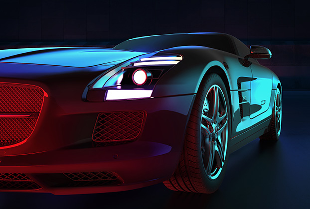 Primo piano della parte anteriore di un'auto sportiva scura illuminata da luci blu e rosse, atmosfera intensa e drammatica